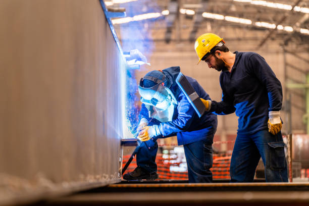engineer teaching apprentice to use welding machine